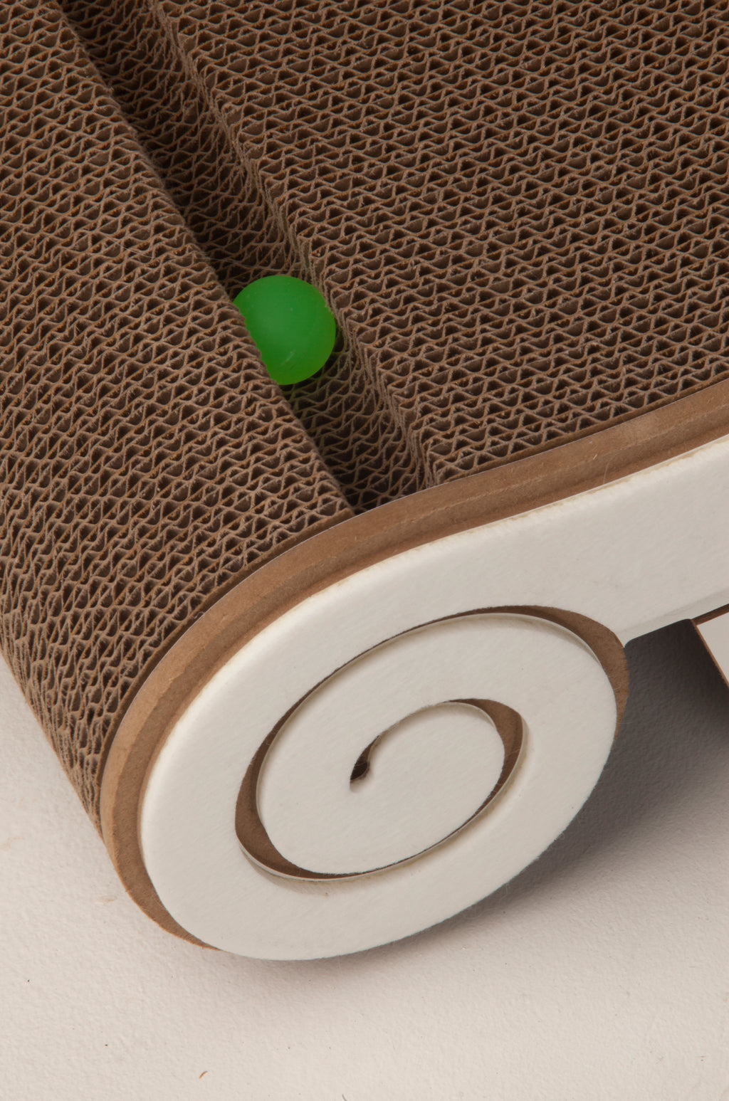 Close-up of the interactive green toy ball inside the track of the corrugated cat scratching board