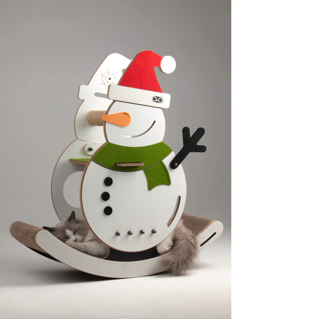 The snowman-themed cat rocker and bed shown with a large fluffy cat resting on its curved 6.6kg scratching base.