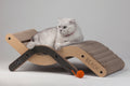 Side view of the Large Nekono Beach Chair Cat Scratcher with a white cat lounging on the curved corrugated surface.