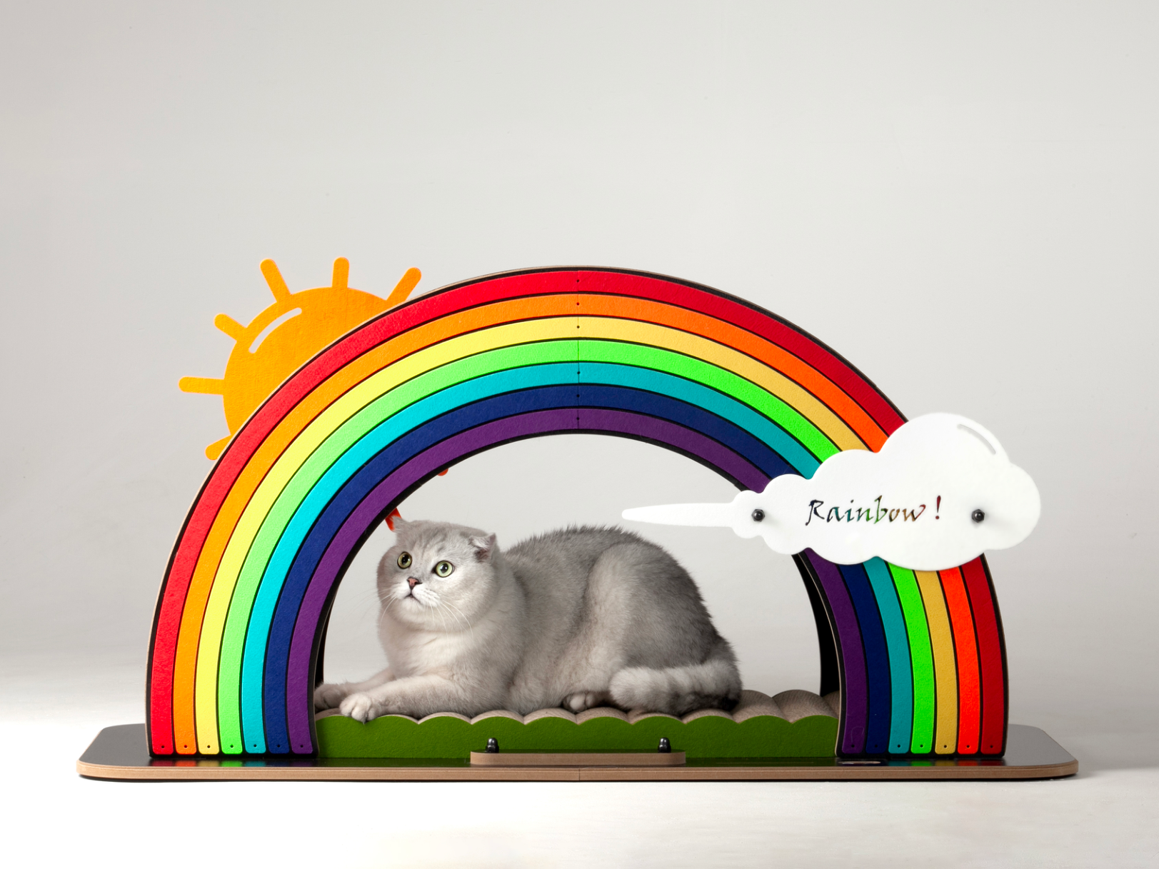 A fluffy white cat napping in the cozy tunnel space underneath the Rainbow Bridge cat scratcher